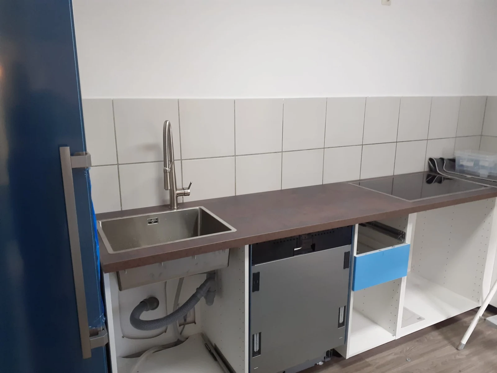 Küchenzeile während der Montage mit Edelstahlspüle, Arbeitsplatte, Kochfeld und offenen Unterschränken