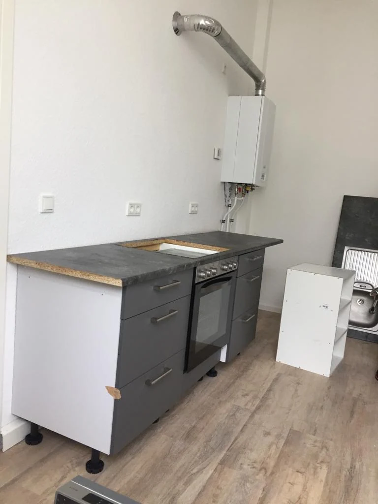 Graue Küchenunterschränke mit Backofen und Arbeitsplatte während der Montage